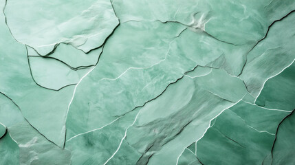 Fototapeta premium Aerial view of a glacier surface showing light green ice with jagged cracks and crevices, forming abstract natural patterns and textures in a rugged landscape.
