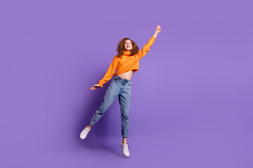 Full size photo of nice young girl jump hand hold empty space wear pullover isolated on violet color background © deagreez