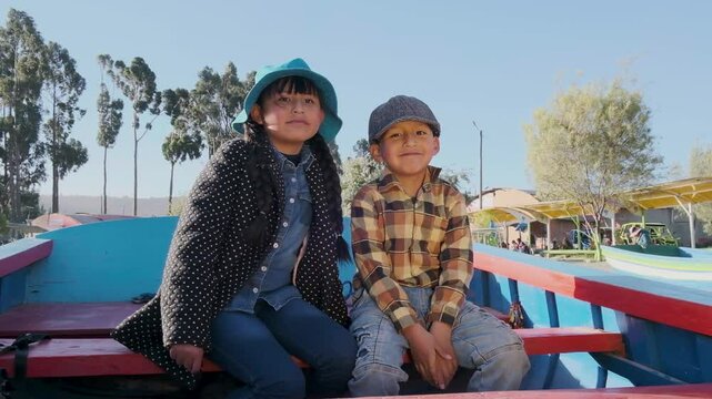 happy latino children looking at the camera while taking a boat ride on a lake titicaca in bolivia - concept of happiness