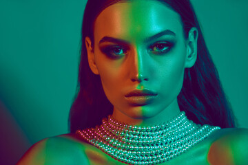 Close-up portrait of young beautiful woman under dual-tone green and blue lighting, highlighting her flawless skin and striking features. Concept of female beauty, art, trendy make-up, party