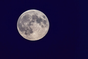 Full moon shining in the dark blue night sky.