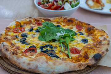 Four seasons pizza. Tomatoes, grated mozzarella, tomato sauce, corn kernels, black olive slices, arugula.