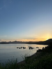 Fototapeta premium Warm Sunset over Quiet Bay with Docked Boats and Dark Hills.