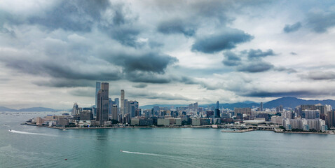 Cloudy skyline view of Hong Kongs waterfront with modern buildings and a serene harbor