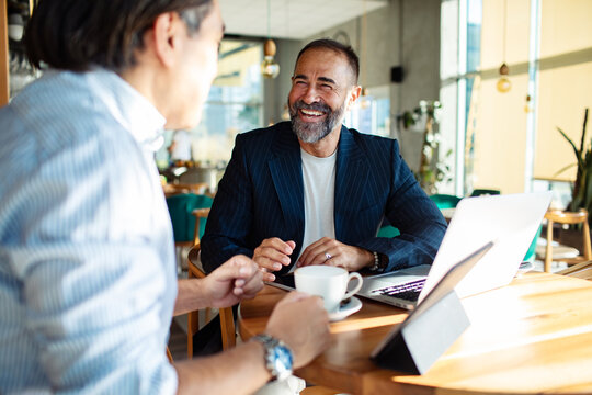 Businessmen discussing strategy over coffee in modern cafe setting