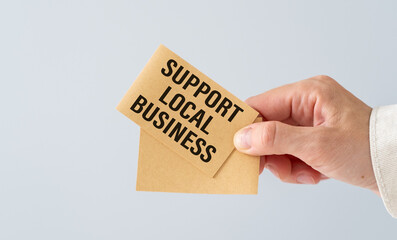 Close-Up Business woman shows a card with text Support Local Business. Business concept