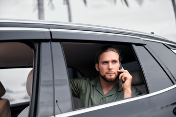 Man talking on phone in a car with palm trees in the background