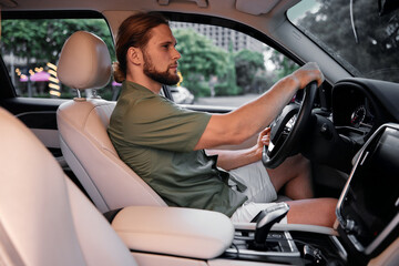 Man driving a car, focused on the road while seated in a modern vehicle with a light interior