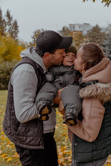 Family in nature in an autumn park kissing a child