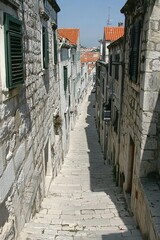 Narrow Cobblestone Street With Stone Buildings, Shutters, and Sunlight, Historic European Town