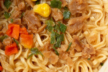 A top down view of the surface layer of a cup of cooked instant ramen.