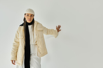 Good looking young woman in stylish warm attire posing on white backdrop.