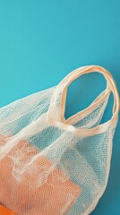 Eco-friendly mesh shopping bag with reusable produce inside on vibrant turquoise background, promoting sustainable lifestyle and zero waste concept.