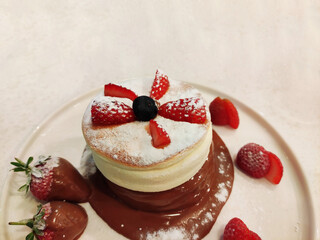  Delicious sweet Japanese dessert, round egg fluffy airy pancakes with chocolate sauce and strawberries, on a white plate