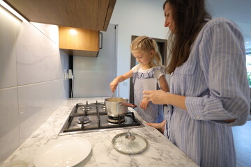 Mother and small daughter cooking food 
