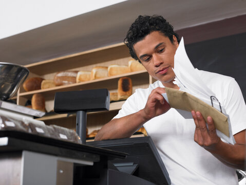 Man Looking at Bills in Deli