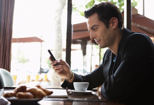 Man Using Cellphone in Cafe