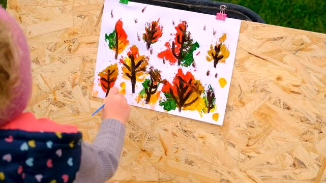 Child drawing autumn leaves. Selective focus.