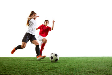Two female athletes in red and white uniforms energetically pursuing ball on soccer field, competing for the victory. Concept of sport, action, competition, dynamic game. Copy space for ad, text