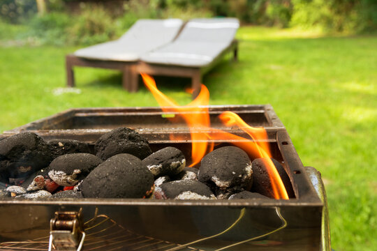 Burning coal briquets on grill in garden