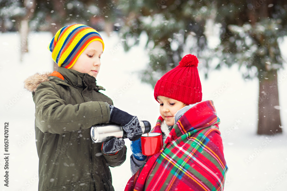 Wall mural happy little smiling girl and teen boy standing outdoor in a winter season and drinking cocoa. holid