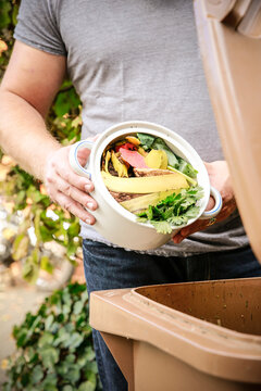 Mature man throwing kitchen scraps into bio-waste container