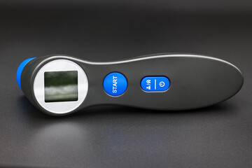 Digital forehead thermometer with LCD display on dark background
