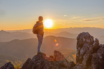 Male hiker with backpack standing on top rock mountain landscape and beautiful view sunset...