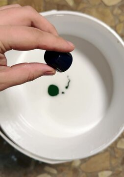Male hand dropping color in the white paint.