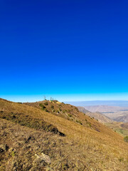 A mountain station on the ridge under a clear blue sky in Kyrgyzstan, with snowy slopes and hills in the background.