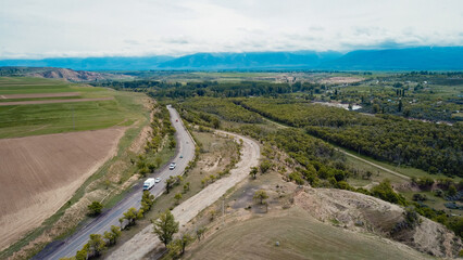 Aerial view of winding road through green landscape in Kyrgyzstan during cloudy weather