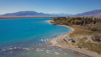 Beautiful turquoise lake in Kyrgyzstan surrounded by mountains and a peaceful shoreline