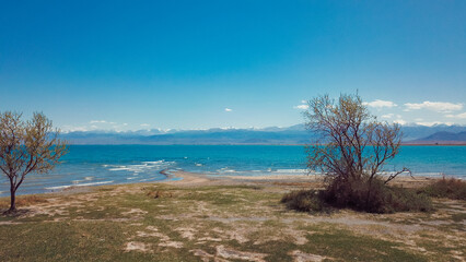 Tranquil shoreline and blue waters of Issyk Kul Lake in Kyrgyzstan under clear skies