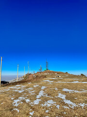 A mountain station on the ridge under a clear blue sky in Kyrgyzstan, with snowy slopes and hills in the background.