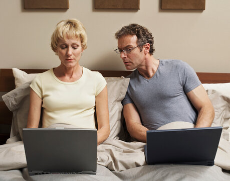 Couple Using Laptop Computers in Bed
