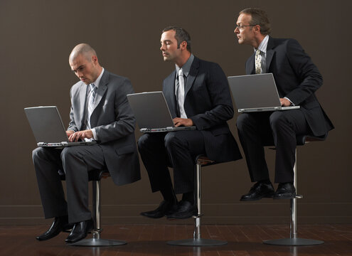 Three Businessmen Using Laptop Computers
