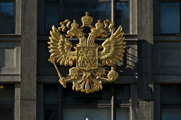 The emblem of the Russian Federation on the facade of the State Duma building. Luxurious golden...
