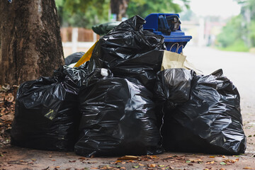 Black plastic garbage bags are placed on the side of a public road.