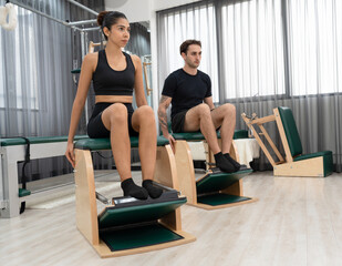 Caucasian woman and men training pilates with pilates equipment in fitness studio	