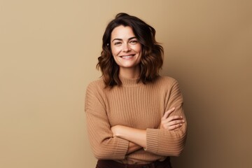 Fototapeta premium Portrait of a satisfied woman in her 30s wearing a cozy sweater over blank studio backdrop