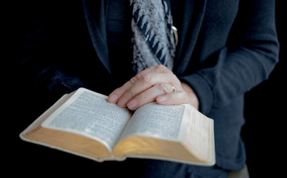 Woman's hands holding an open Bible; Studio
