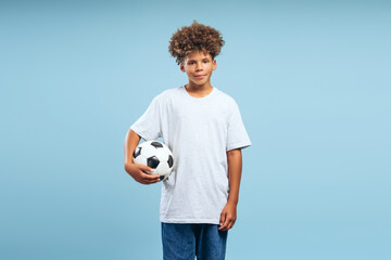 Happy teenager, African American boy, soccer player wearing blue t shirt holding soccer ball