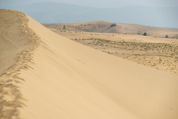 Golden desert dunes illuminated by sunbeams under a dramatic sky