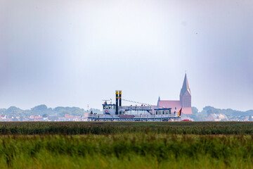 Obraz premium Raddampfer auf dem Bodden hinter dem Deich mit Barth im Hintergrund.