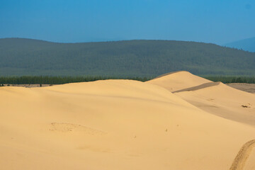 Golden desert dunes illuminated by sunbeams under a dramatic sky