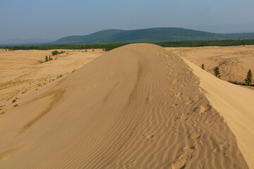 Golden desert dunes illuminated by sunbeams under a dramatic sky