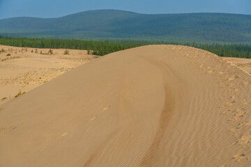 Golden desert dunes illuminated by sunbeams under a dramatic sky