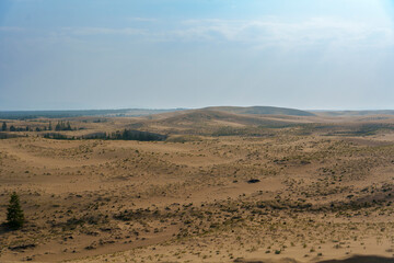 Golden desert dunes illuminated by sunbeams under a dramatic sky