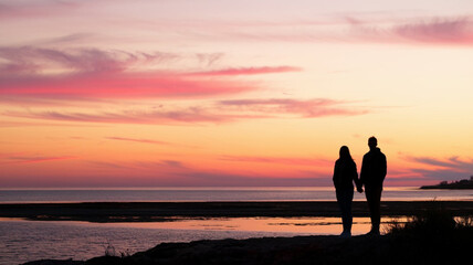 Fototapeta premium Man and woman walking on beach at sunset