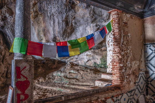 Buddhist prayer flags and grafitti in the historic Santa Margarida cave on the coast of Portugal; Setubal, Portugal
